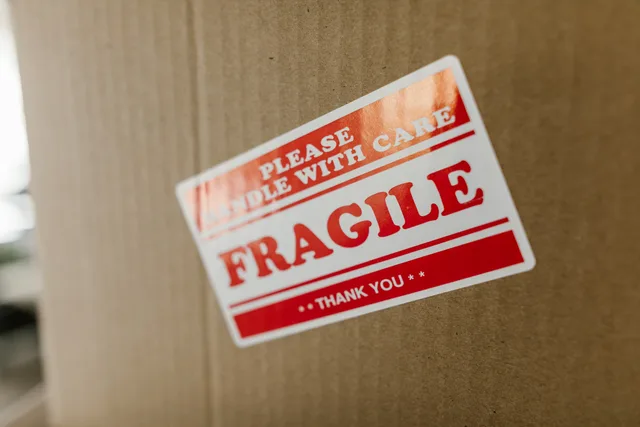 Close-up of a cardboard box with a 'fragile' sticker indicating careful handling. Preventing duplicate shipping labels during dispatch